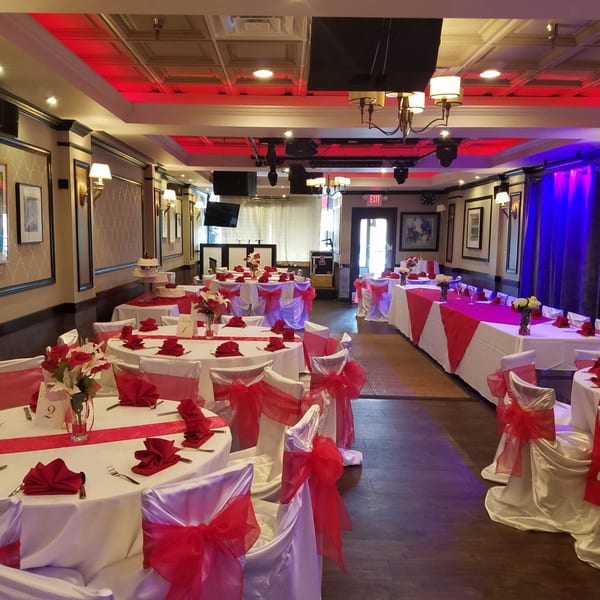 Elegant dining room at Tipicos Los Amigos, set with white tablecloths, red runners, and chair bows.