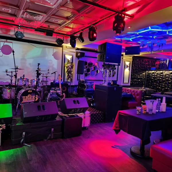 A vibrant, neon-lit stage with a drum set and musical equipment, ready for a performance.