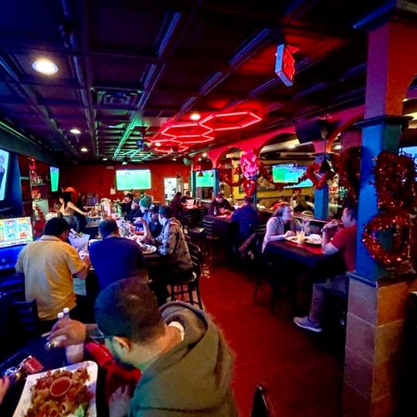Diners enjoying food and drinks in the vibrant, red-lit interior of Tipicos Los Amigos restaurant.