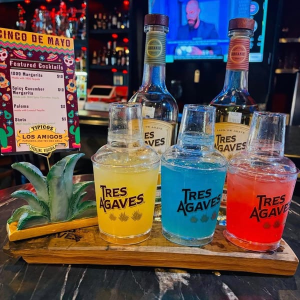 Colorful Tres Agaves tequila shots and bottles on a wooden tray, with a Cinco de Mayo menu.