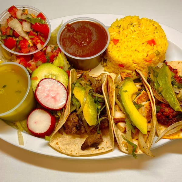 Three Salvadoran tacos with various fillings, avocado, rice, salsa, and radishes on a white plate.